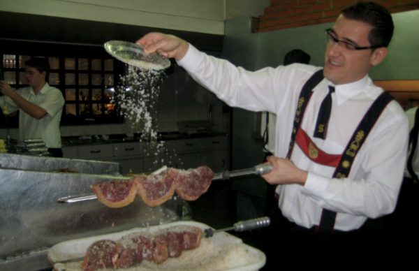 Garçom salgando espetos de picanha em um restaurante brasileiro